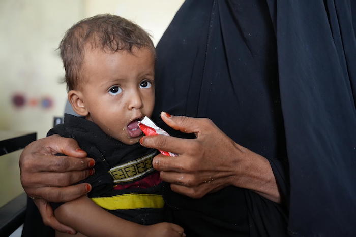 A child being fed ready-to-use therapeutic food by his caregiver