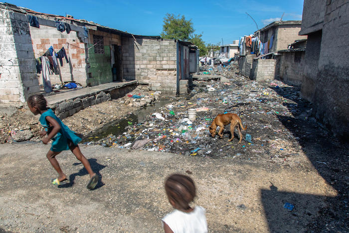 Children run past piles of garbage in a residential area of Cite Soleil, Haiti.