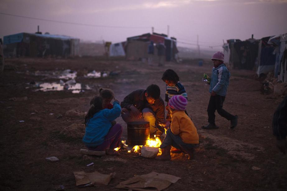 Syrian refugee children warm themselves by a fire in an encampment near Baalbek, Lebanon. 