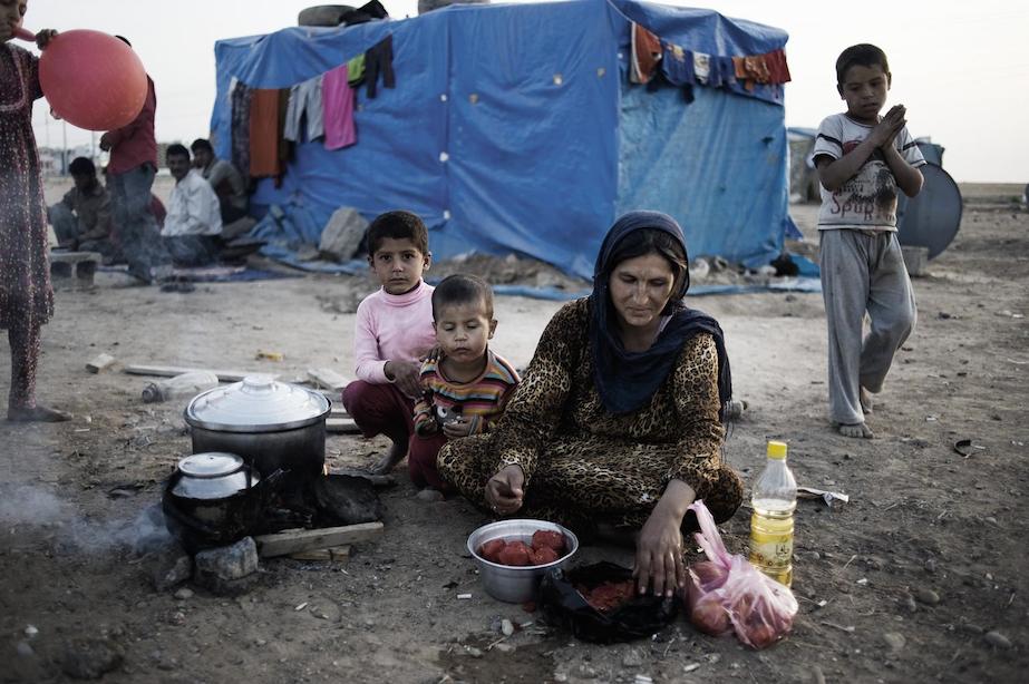 A woman and three children prepare a meal at a makeshift outdoor cooking area, in the Kawergosk camp for Syrian refugees, just west of Erbil, the capital of Kurdistan Region. By 14 November, the camp was hosting over 13,100 refugees.