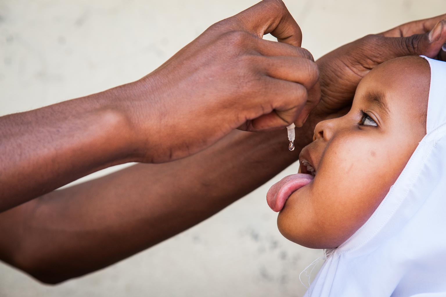 A little girl from Somalia receives a dose of oral polio vaccine during an emergency immunization campaign UNICEF and partners waged in 2013 after Somalia experienced its first rash of cases since 2007.  Image: UNI155431 Credit: © UNICEF/NYHQ2013-1317/Oha