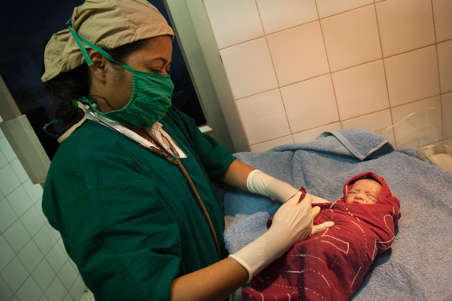 A doctor wraps up a newborn boy with clothes right after delivery at BSMMU, Dhaka on 2 February 2014.