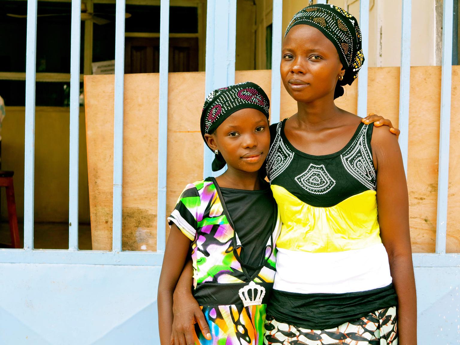 In July 2014 in Sierra Leone, Fatmata Sesay stands with her 11-year-old daughter, Tata, both survivors of Ebola virus disease (EVD), in the city of Kenema, Eastern Province.