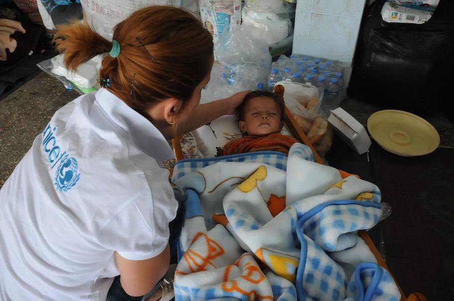 A UNICEF staff member checks on a sleeping child, in a classroom at Regional Primary Boarding School-YIBO in the district of Suruç in Sanliurfa Province.