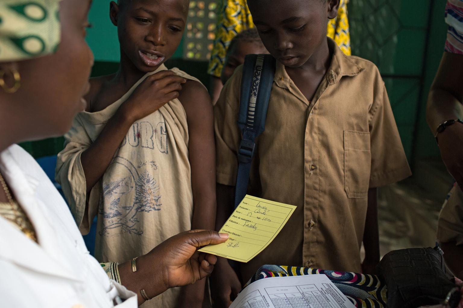 A nurse gives children their vaccination cards to show they received measles and polio vaccinations, as well as deworming pills and Vitamin A supplements at the Madina Health Centre in Guinea.  In April, for the first time since the Ebola outbreak, Guinea