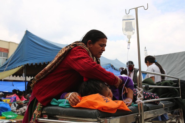 A mother tends to her daughter at a hospital in Kathmandu after the earthquake. Most patients have been moved outside to the courtyard.