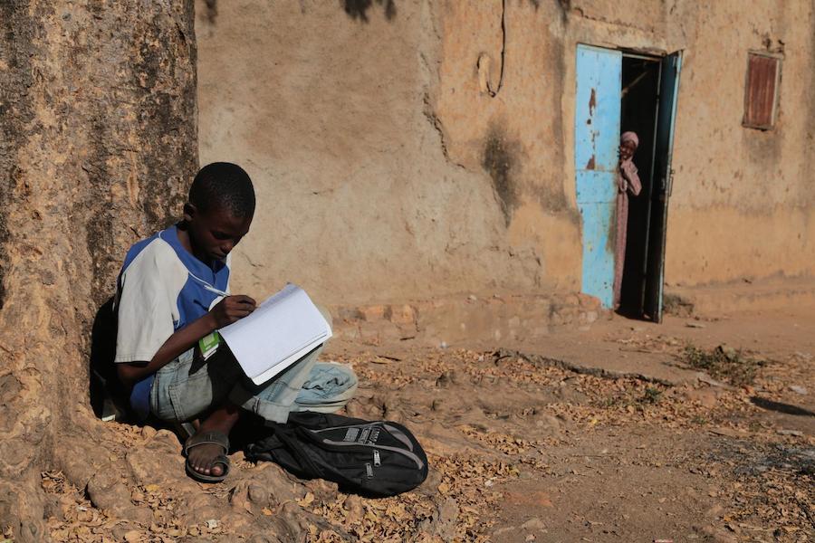 Ahmad completes his homework while seated on the ground in Moundou, Chad.