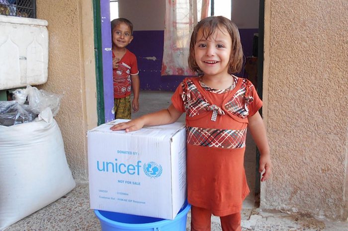 Children displaced by ongoing violence in Ramadi stand next to an RRM kit in the doorway of their informal shelter in Amriyat Al Falluja in Anbar Governorate.