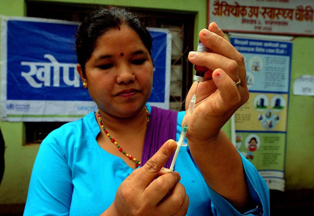 On 20 August 2015, Auxiliary Nurse Midwife Mithu Bhujel extracts Measles and Rubella vaccine in a syringe to immunize children at Jaisithok sub health post in Kavrepalanchok district.