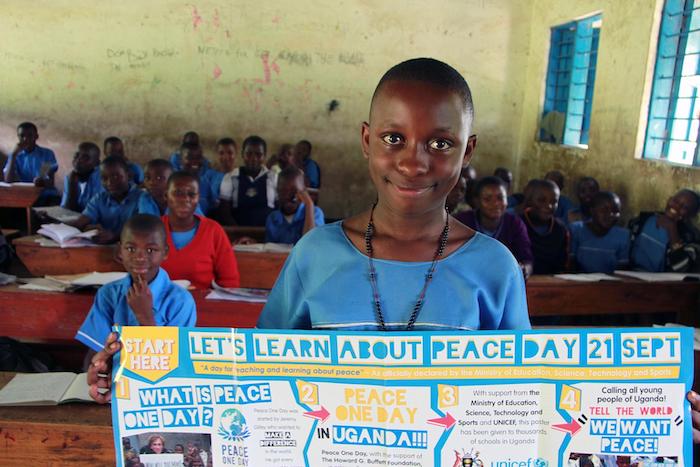 Ritah, a primary school student in western Uganda, holds up a poster promoting peace.