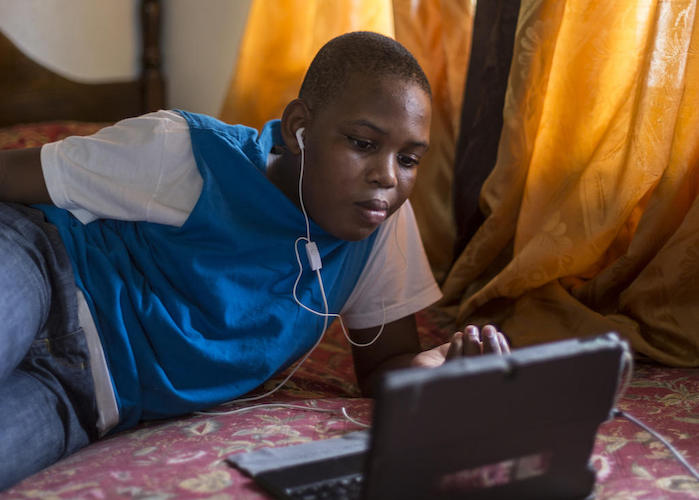 James Jr., 13, plays video games in his family's rented house in St. John's, Antigua in November 2019. His family was displaced from Barbuda by Hurricane Irma in 2017. 