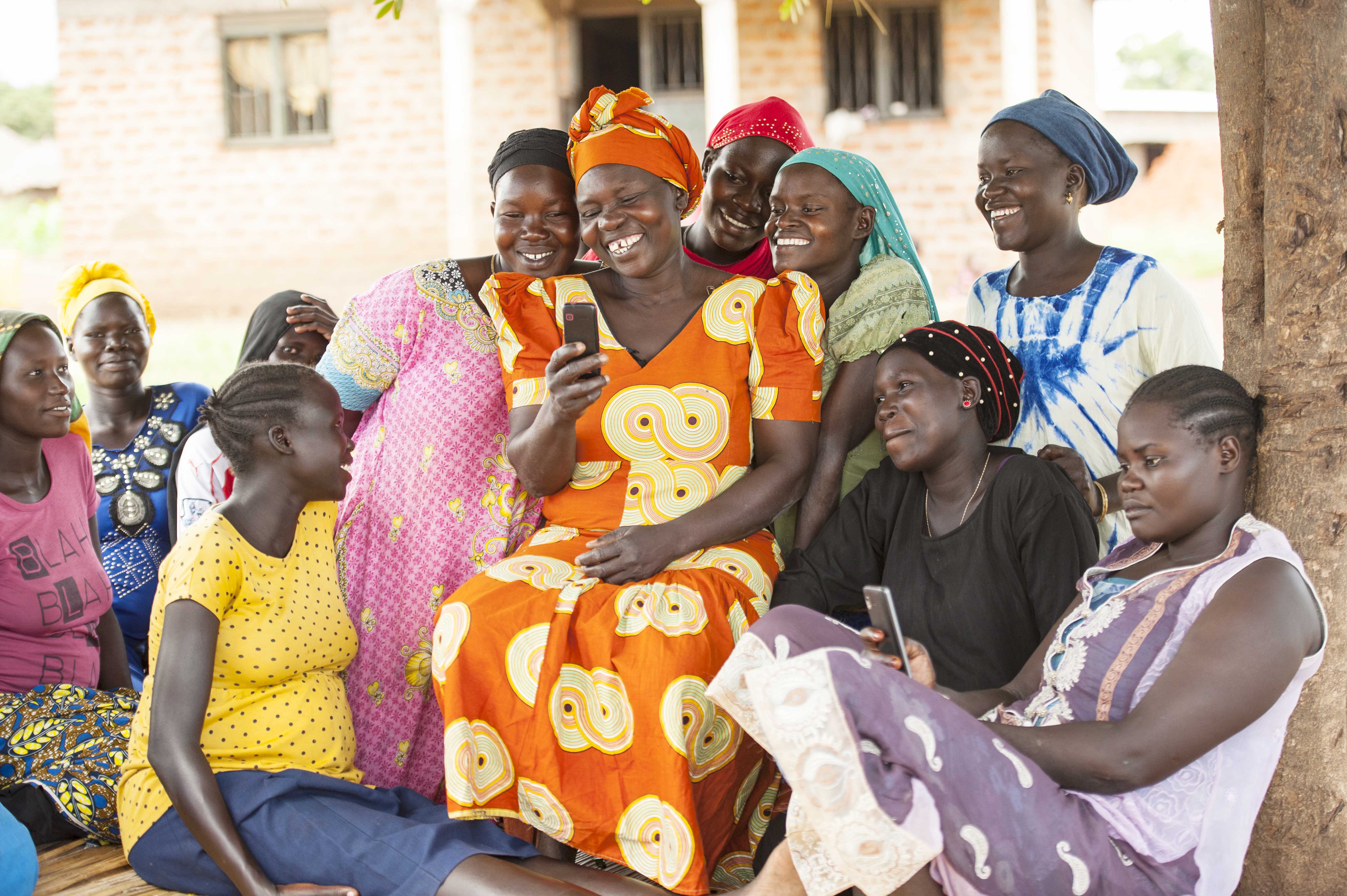 Women of Manduru village, Yumbe District, Uganda, discuss text messages received on a phone from UNICEF innovation program FamilyConnect, which connects women and children to healthcare services. ©UNICEF/UNI232737/Kabuye