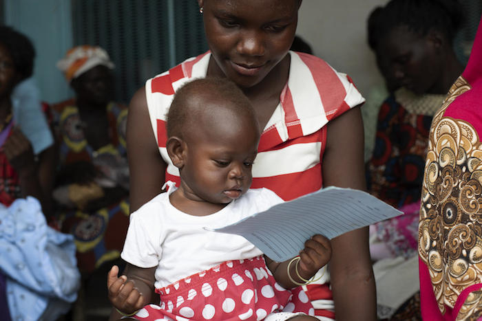 An infant plays with her immunization record while waiting to get her measles vaccine at Nyakuron Primary Health Care Centre in Juba, South Sudan, where UNICEF is supporting immunization efforts that had lapsed due to ongoing conflict in the country.