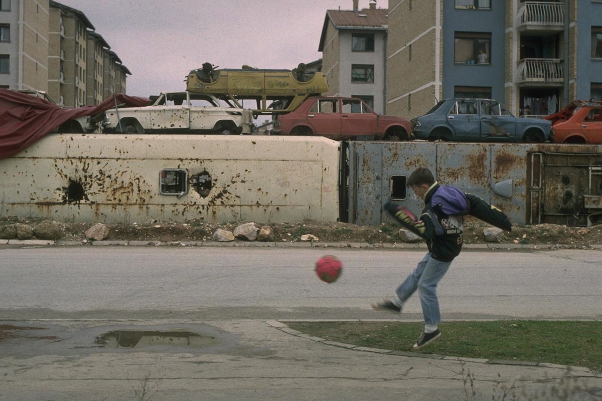 1994-A boy plays soccer on the street in the heavily damaged "front line" suburb of Dobrinja in the besieged capital city of Sarajevo.