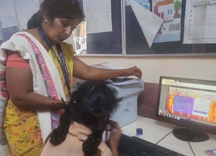 A science teacher in India teaching a student in front of a computer