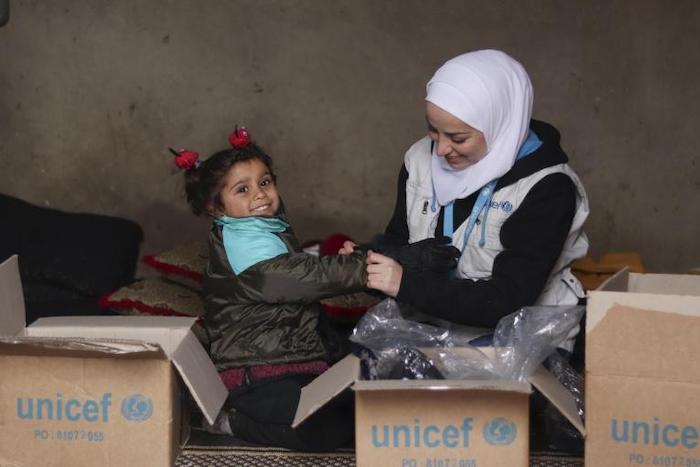 A UNICEF staff member helps out a child in Syria.