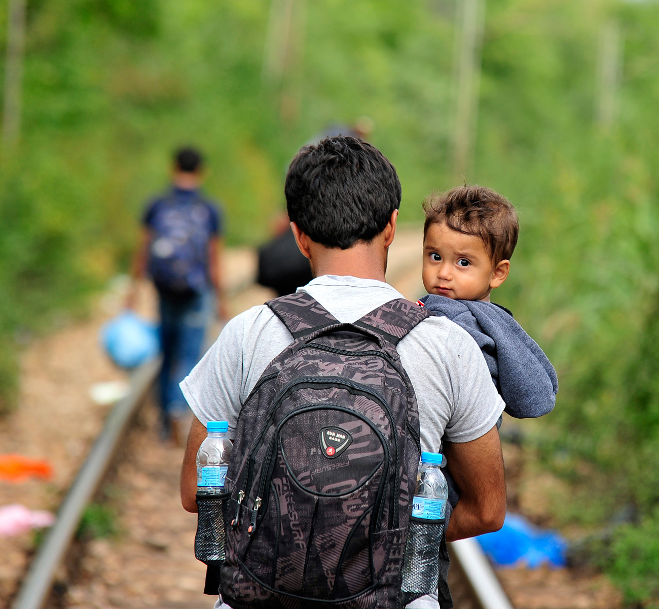 A father holds a young son while he walks the long road through Macedonia. Donation Form Background