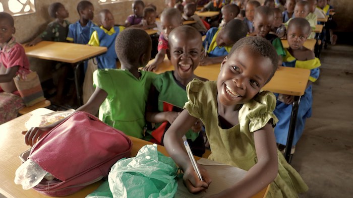 At Mlomba primary school, students use a desk to write for the first time. The school received 300 desks from K.I.N.D. campaign, through UNICEF Malawi. © UNICEF/Chagara/2016