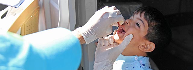 A child receives a vaccine by a practitioner in PPE