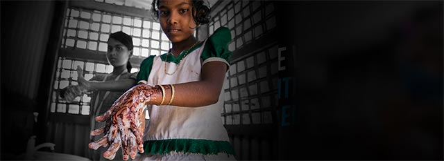 A girl washes her hands at a public sink
