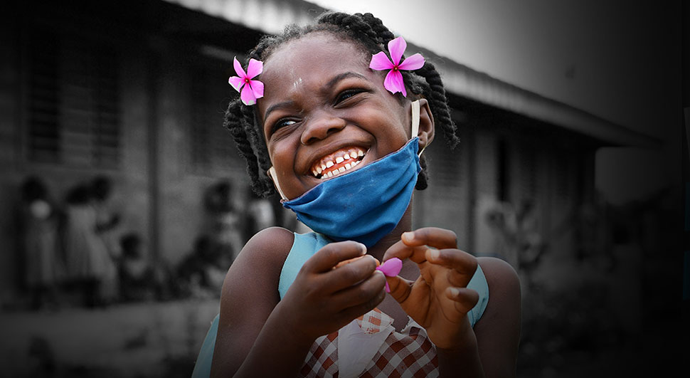 a girl smiles in a face mask at an outdoor school setting