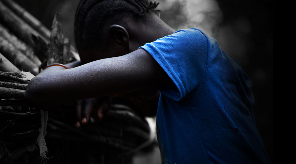 a boy is slumped over, his face buried in his crossed arms