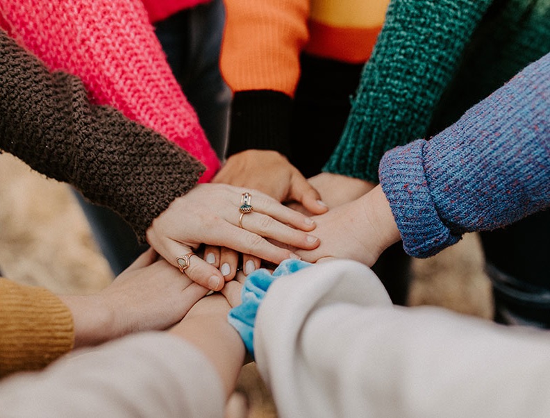 a group of children's hands are stacked on top of each other in a solidarity gesture