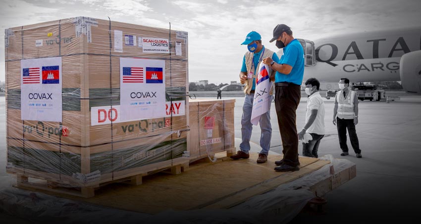two UNICEF workers oversee COVAX crates on an airport runway, in front of a Qatar Cargo airplane