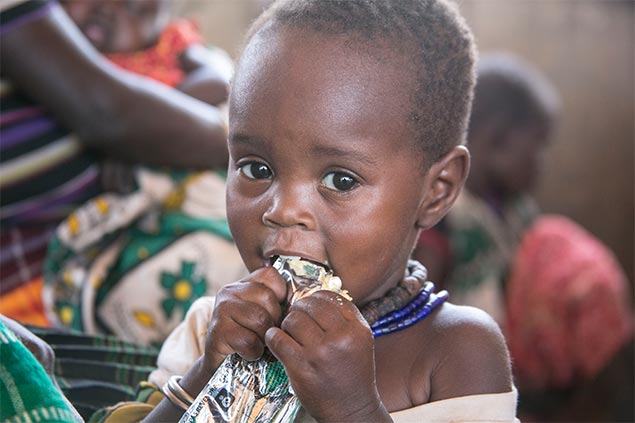 A boy munches on food in a wrapper