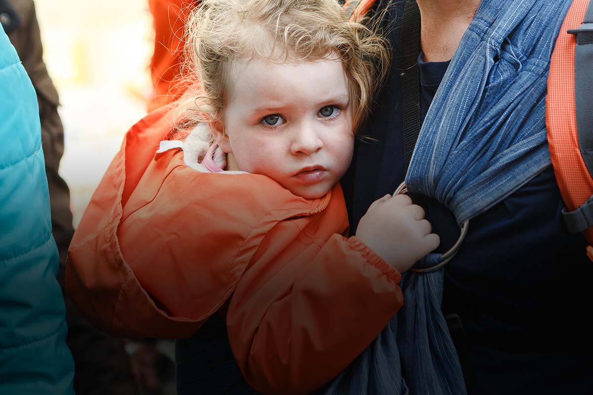 A child clings to an adult's chest by their sarong