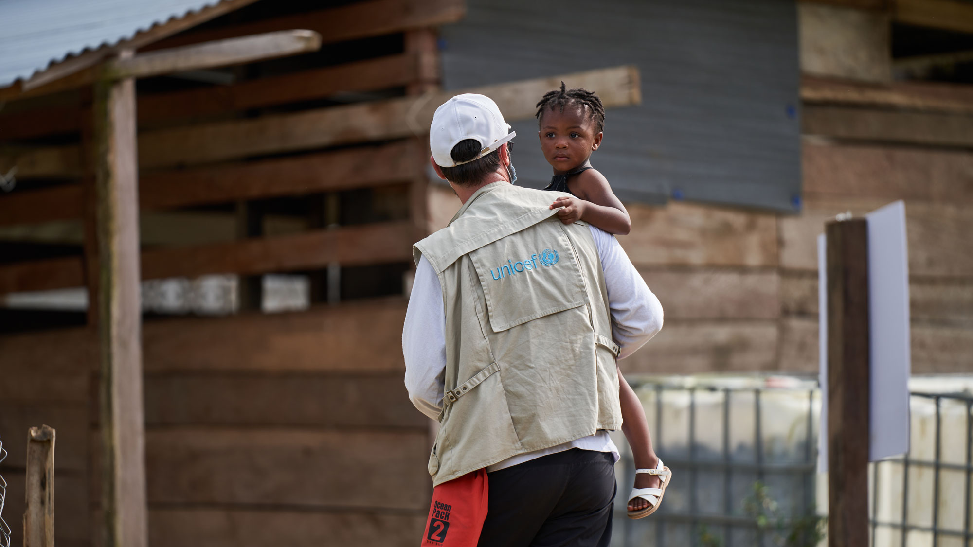 Alfonso F. Reca, UNICEF Regional Communications Specialist for UNICEF in Latin America and the Caribbean, carries a young girl who has just arrived with her mother in Bajo Chiquito, Darién, Panamá, after migrating through the dangerous Darién Gap.