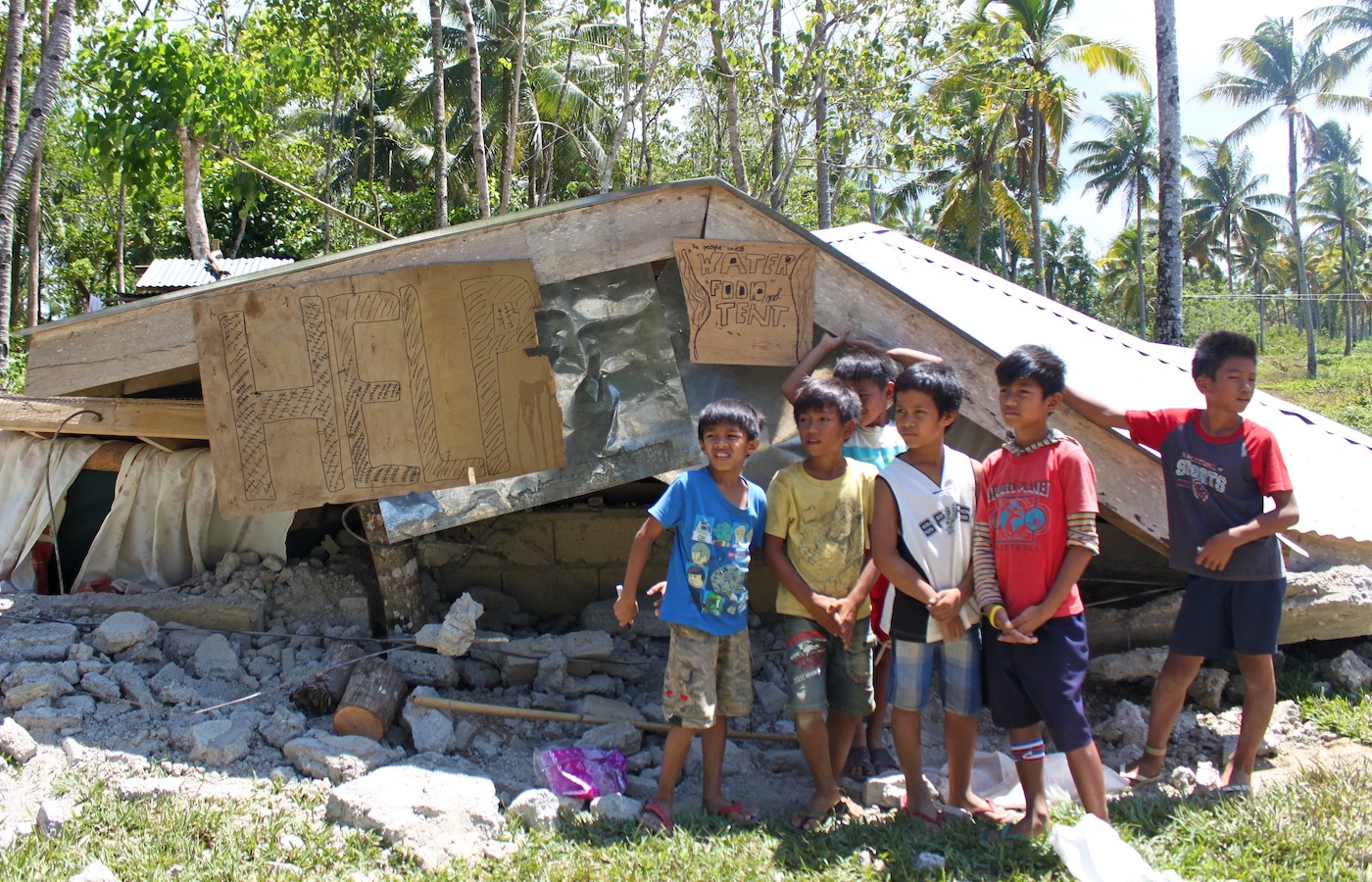 Children affected by the earthquake stand in front of a collapsed house in Bohol, Philippines. ©UNOCHA 2013/JAddawe
