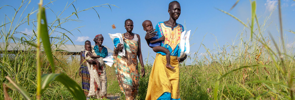 Women in Bienythiang, Akoka County, Upper Nile state, South Sudan carry UNICEF-supplied mosquito nets.