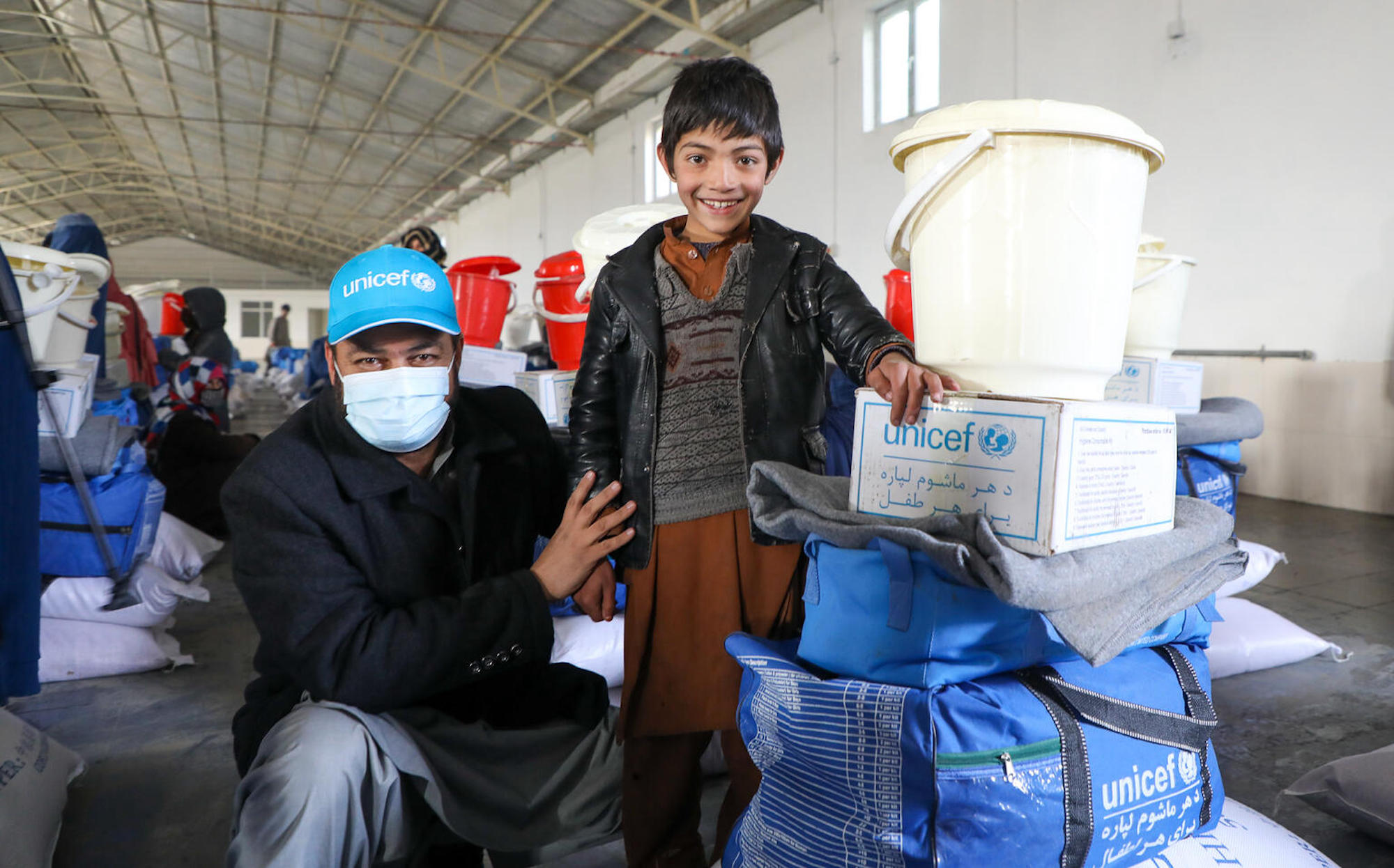 On Jan. 18, 2022, in Kabul, Afghanistan,11-year-old Hadi thanks Mohammad Khalid Azami, WASH Officer at UNICEF Afghanistan, for the winter gear he has just received from UNICEF.