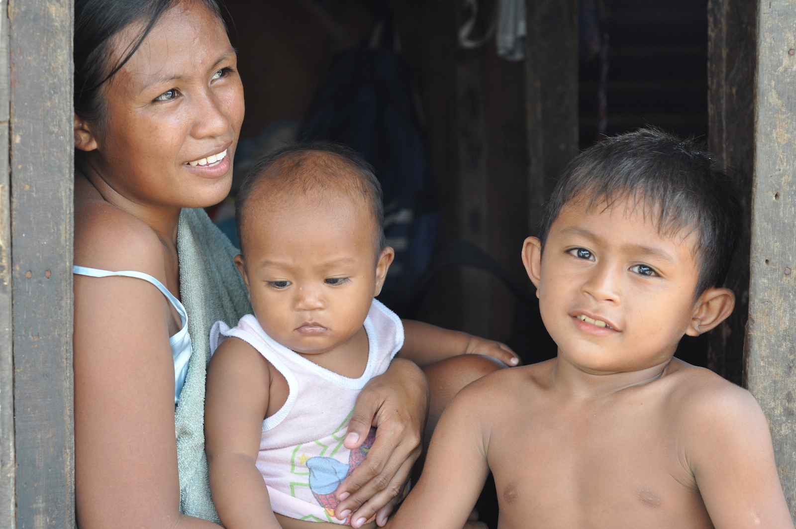 Gerald Alcaraz (right) sits in the doorway of the small family home in Tacloban, Philippines with his mother Richelle and his younger brother Jeffrey
