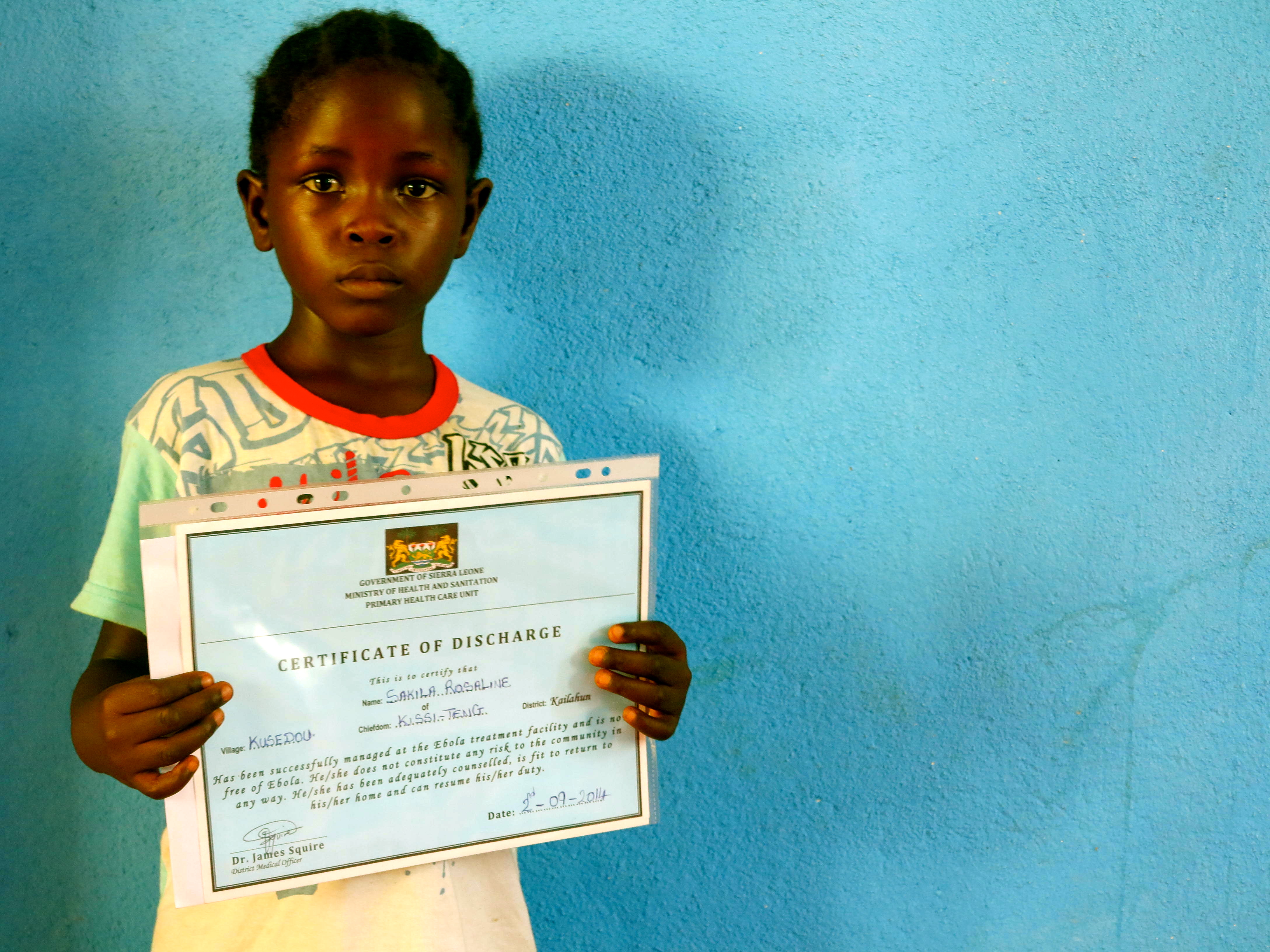 Rose shows off her certificate of good health that was issued to her by the Ministry of Health and Sanitation when she left the Ebola treatment center in Sierra Leone. 
