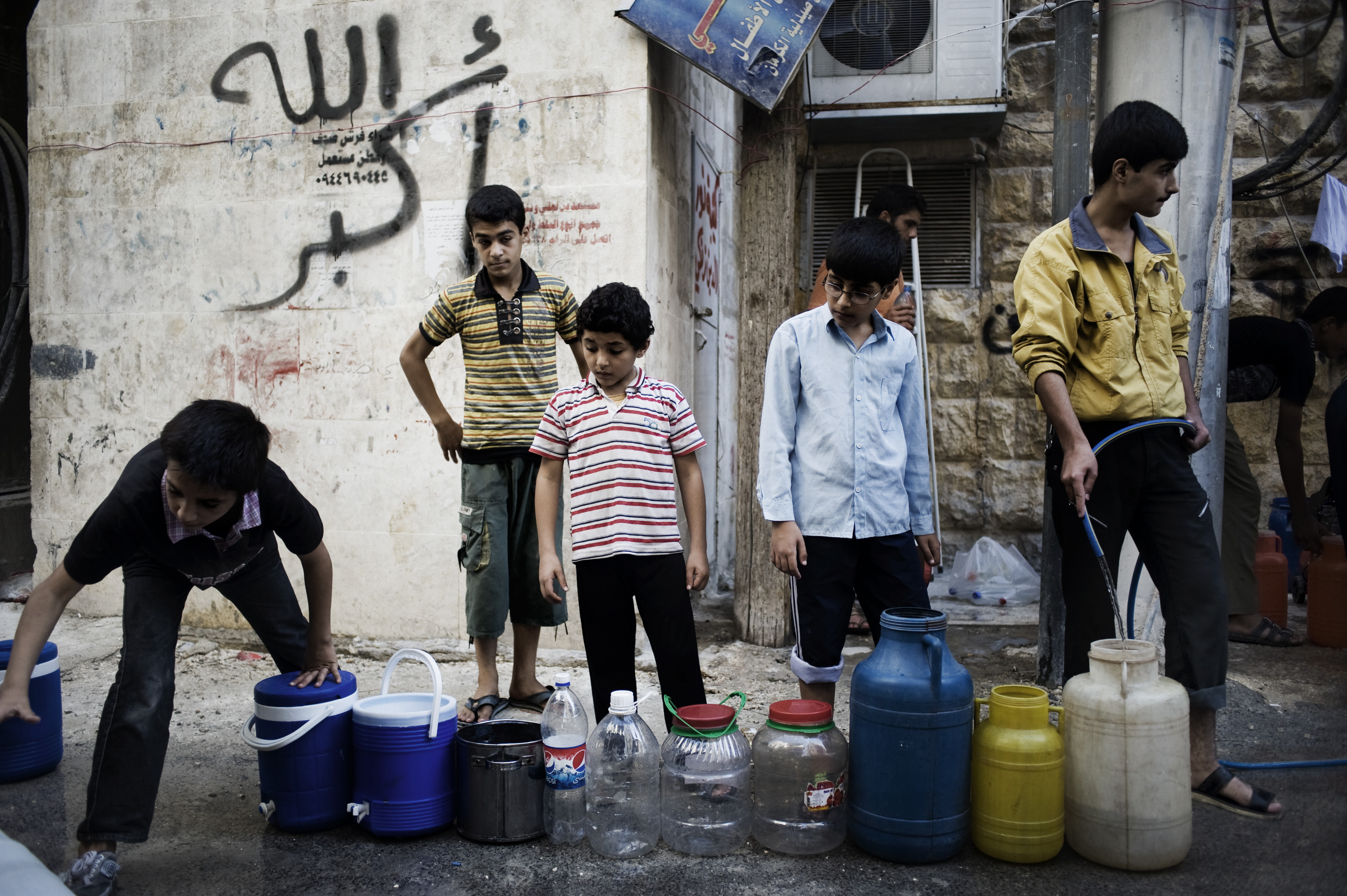 Syrian boys line up to fill jerrycans and other containers with water in Aleppo, Syria.