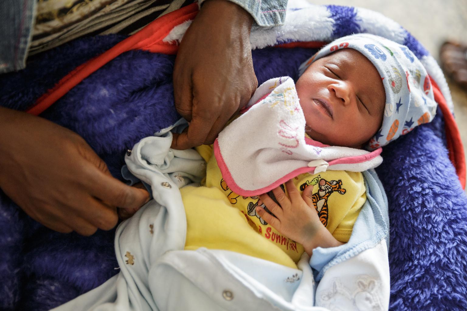 A baby on his mother's lap waits to receive the BCG vaccine in Sierra Leone.