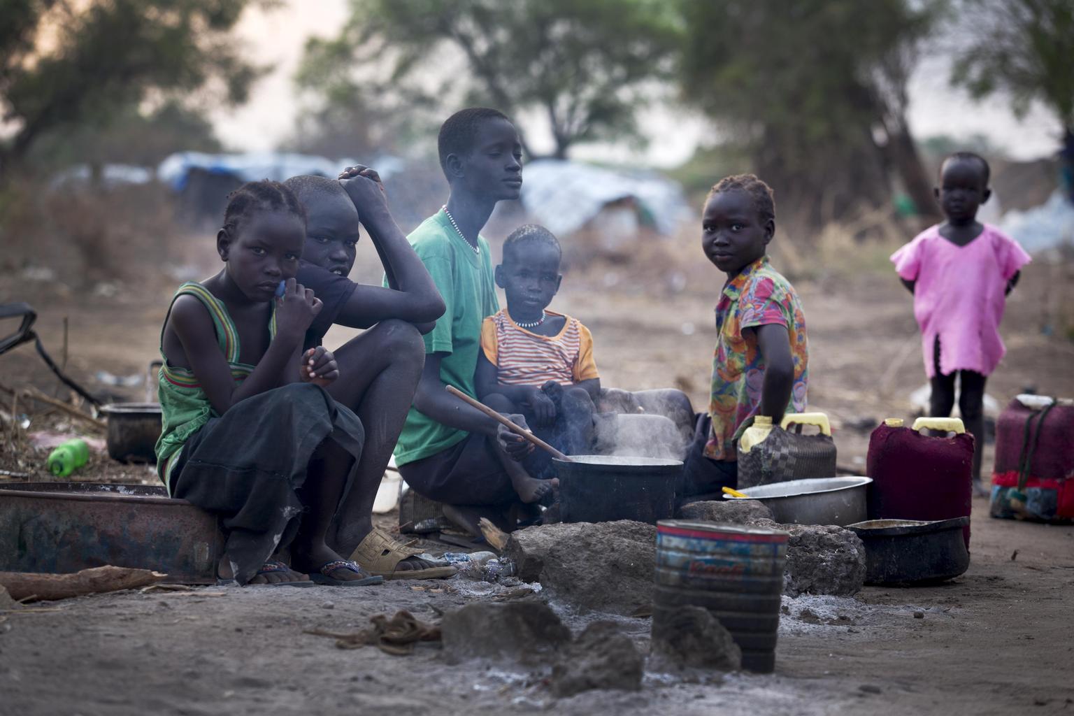 Displaced children gather at a cooking fire in the town of Mingkaman, South Sudan.
