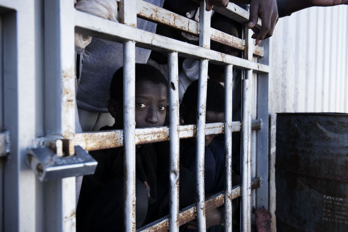 Child migrant looking through the bars of a detention cell in Libya.