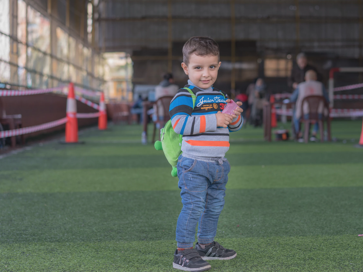 Syrian refugee child in Lebanon holds his mother's new LOUISE common card, which will allow the family to access all the cash-based aid programs for which they are eligible.