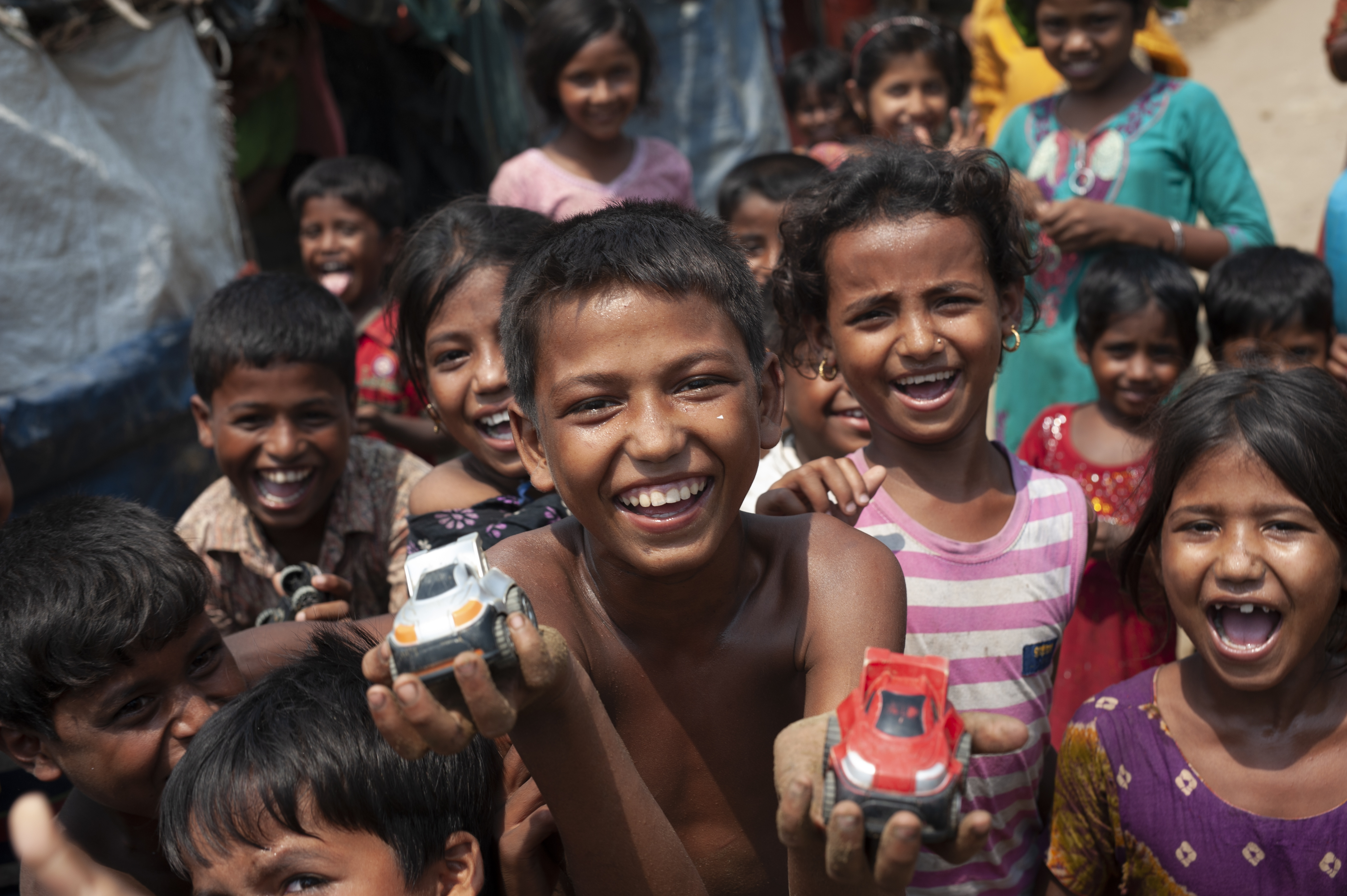 Mohammad Rifat, 12, (shirtless, center) and his friends race toy cars down a sandy stretch of trail in Shamlapur camp, Cox's Bazar District, Bangladesh on April 22 2018