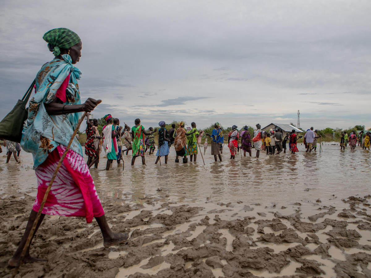 Displaced families make their way back to temporary housing through flood water after a distribution point ran out of supplies in Pibor, Boma State, South Sudan on November 6, 2019. 