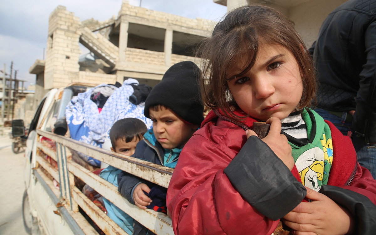 Children ride on the back of a truck heading out of south rural Idlib, northwest Syria, where escalating hostilities have forced some 875,000 Syrians to flee since December 2019.