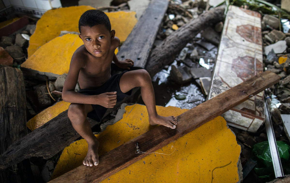 A boy in Bilwi, Nicaragua, sits on what remains of the family home in the wake of Hurricane Iota.