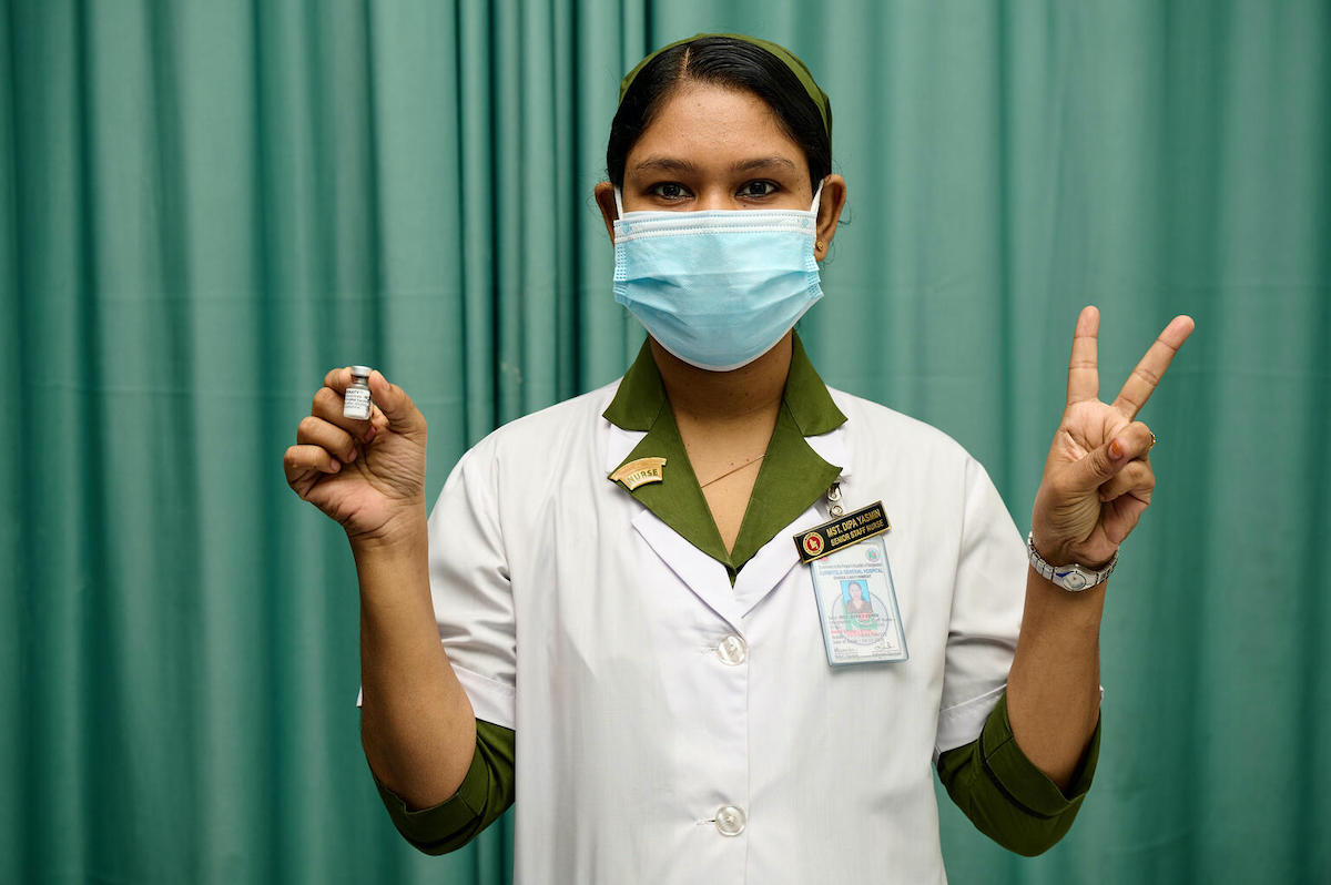 A trained vaccinator at Kurmitola General Hospital, Dhaka, Bangladesh, flashes V for victory — also V for vaccine — as COVID-19 vaccinations ramp up in the country, with support from UNICEF and the COVAX Facility.