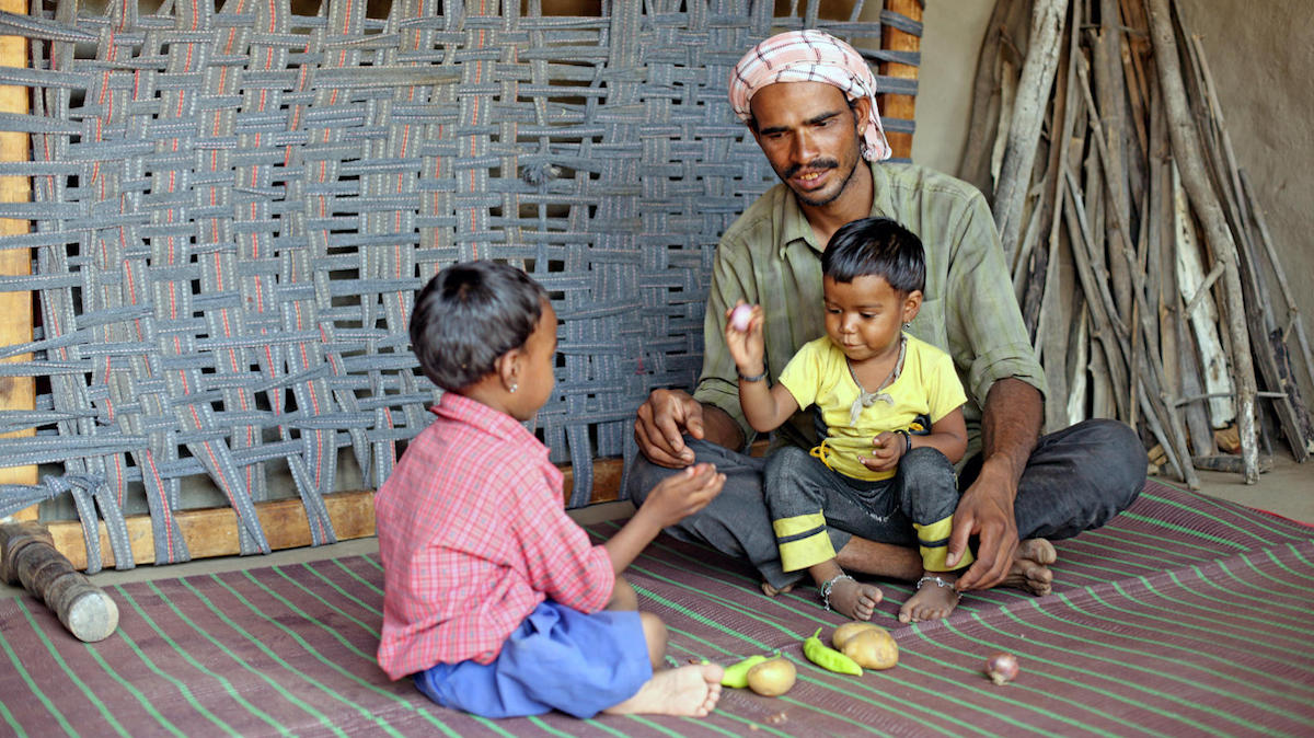 A father in Odisha, India, who receives early childhood care education with UNICEF's support engages with his young children.