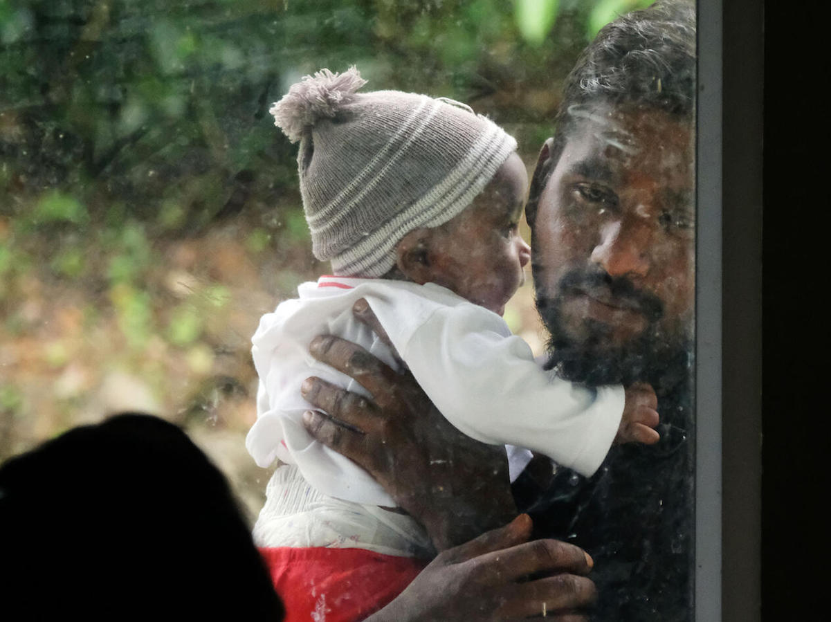 Murugayya Gunasekara, 30, holds his child outside the UNICEF-supported health clinic in the tea estate area in Hatton, central Sri Lanka. 