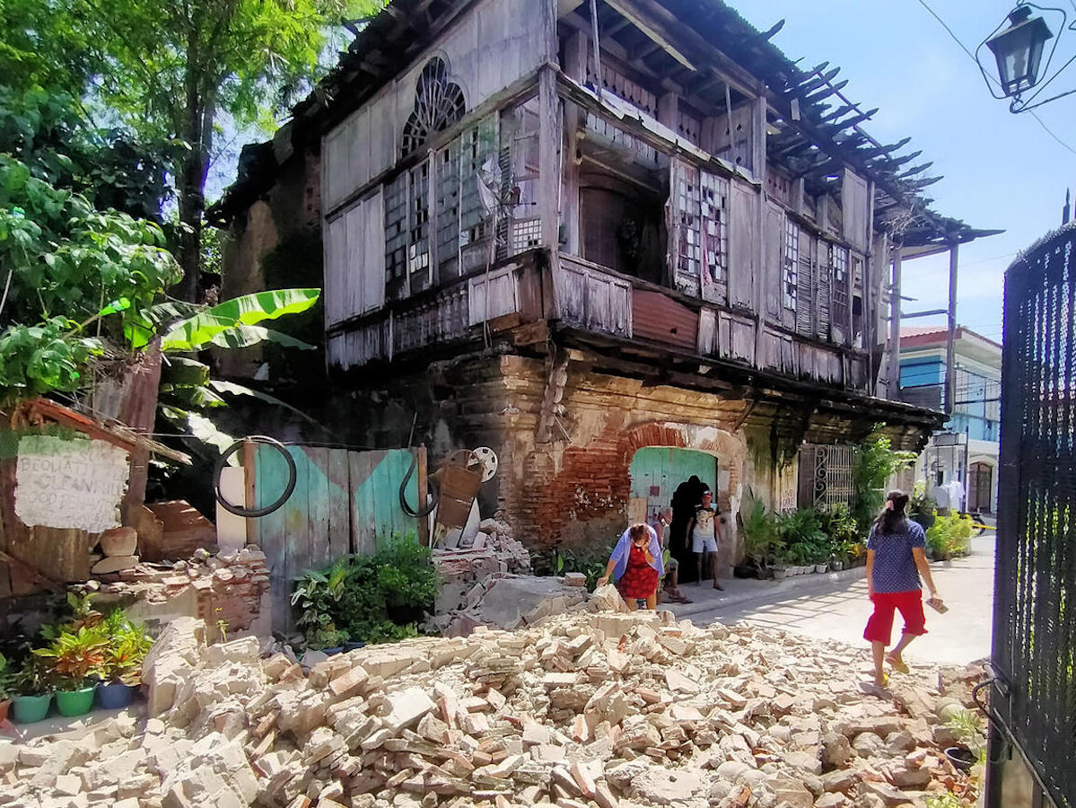 On July 27, 2022, residents walk past debris from an old house in Vigan City, Ilocos Sur province, north of Manila, after a 7.0-magnitude earthquake hit the northern Philippines.