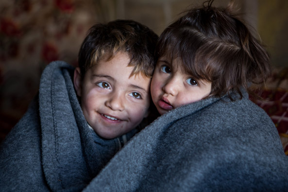 Hakim and Amira wrapped up in their new Unicef blankets peep out of a tent in a Syrian refugee camp in Iraq